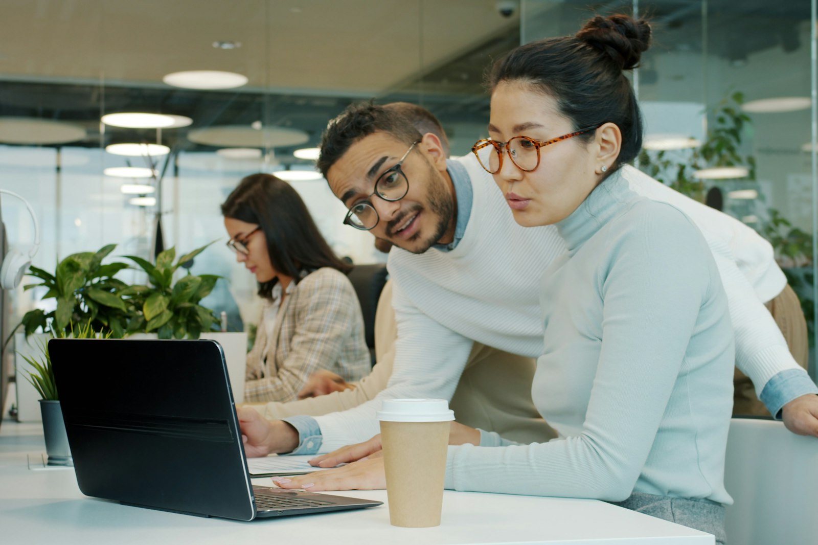 Colleagues working together at a laptop in a bright office